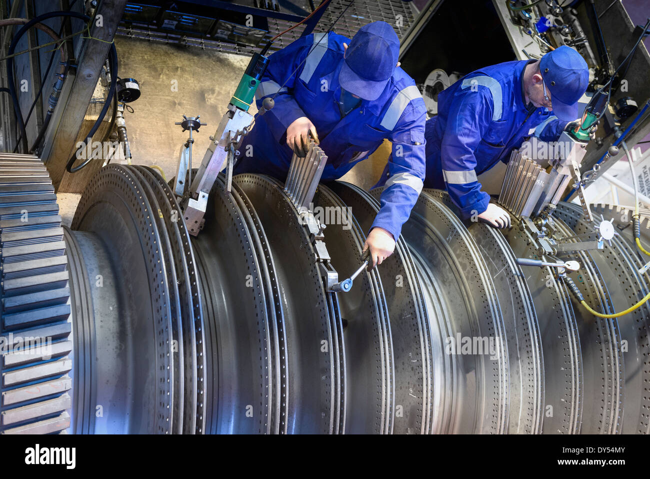 Engineers fitting blades to steam turbine in turbine repair bay Stock Photo