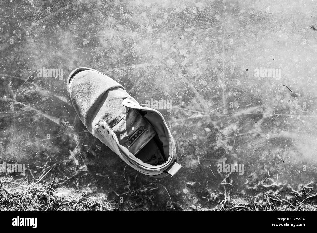 Worn sports shoe on the frozen puddle Stock Photo