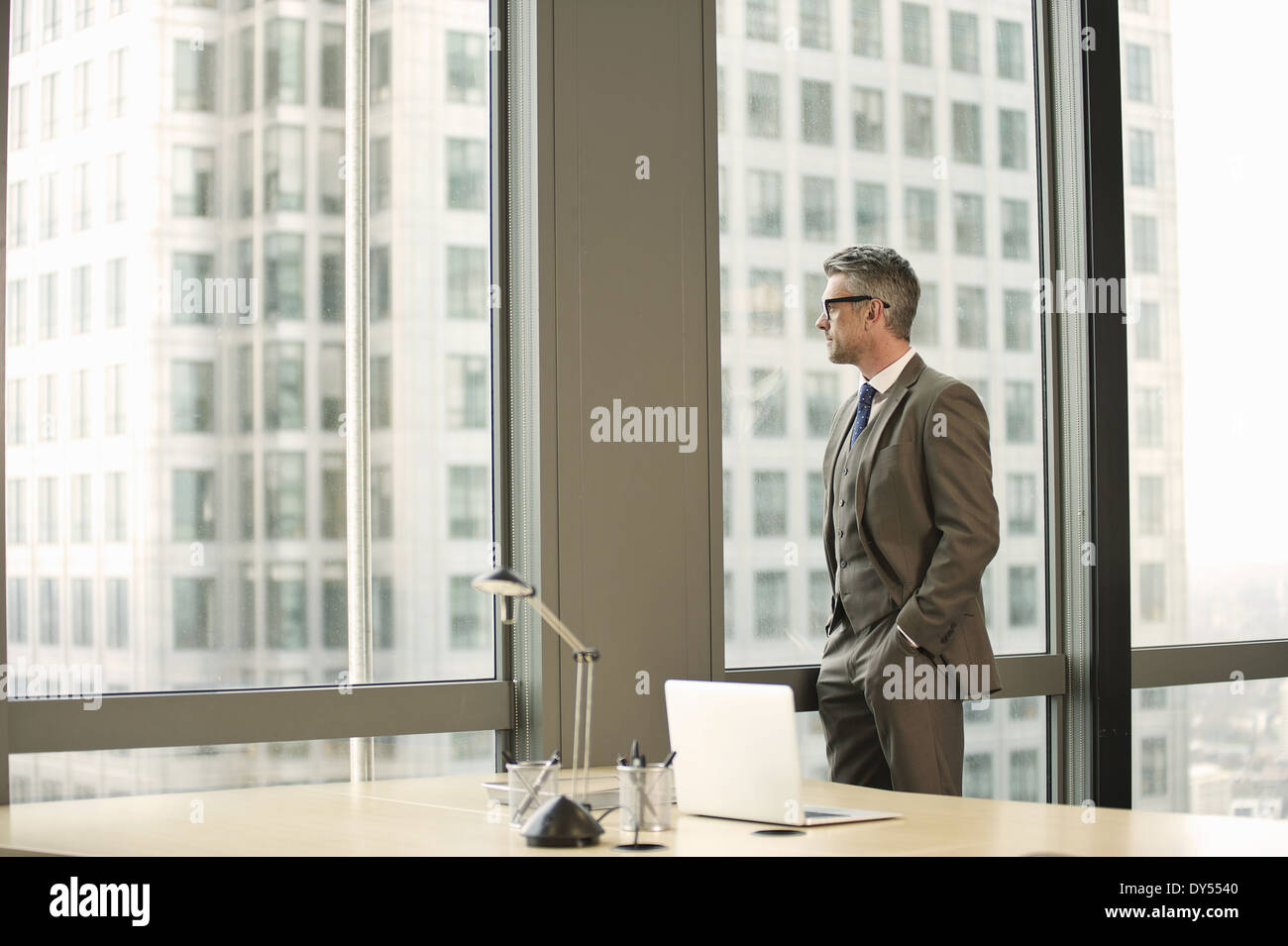 Businessman looking out of office window Stock Photo