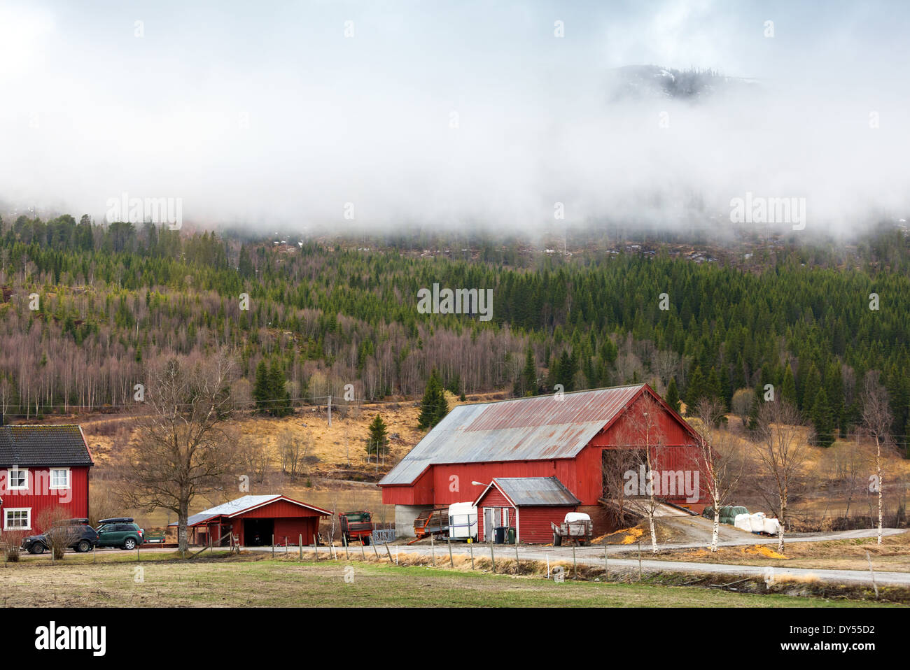 Rural Norwegian landscape with red wooden houses and clouds on hills Stock Photo
