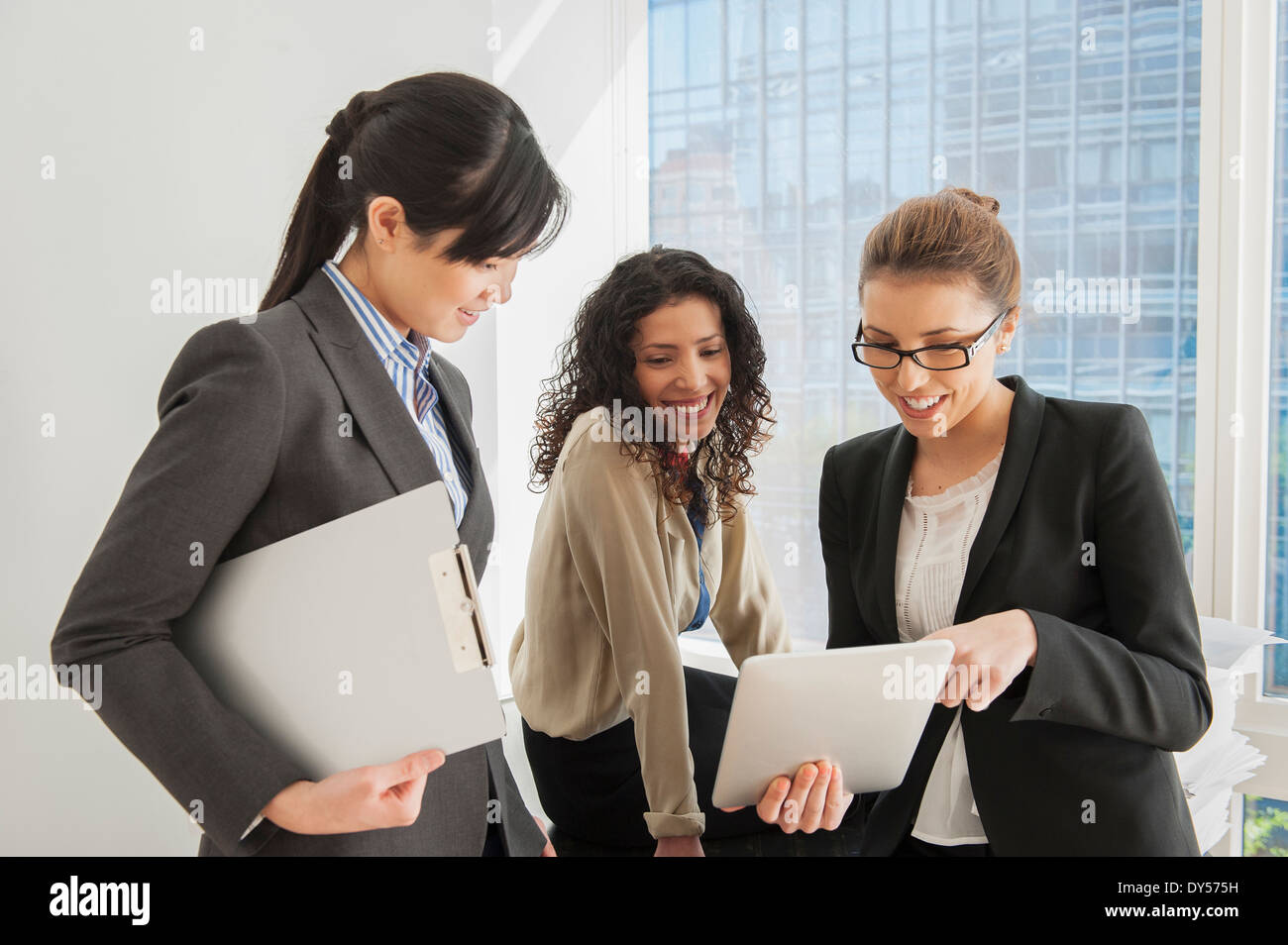 Three businesswomen sharing ideas on digital tablet Stock Photo