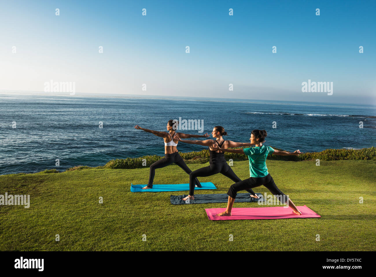 Women on cliff, in yoga positions Stock Photo