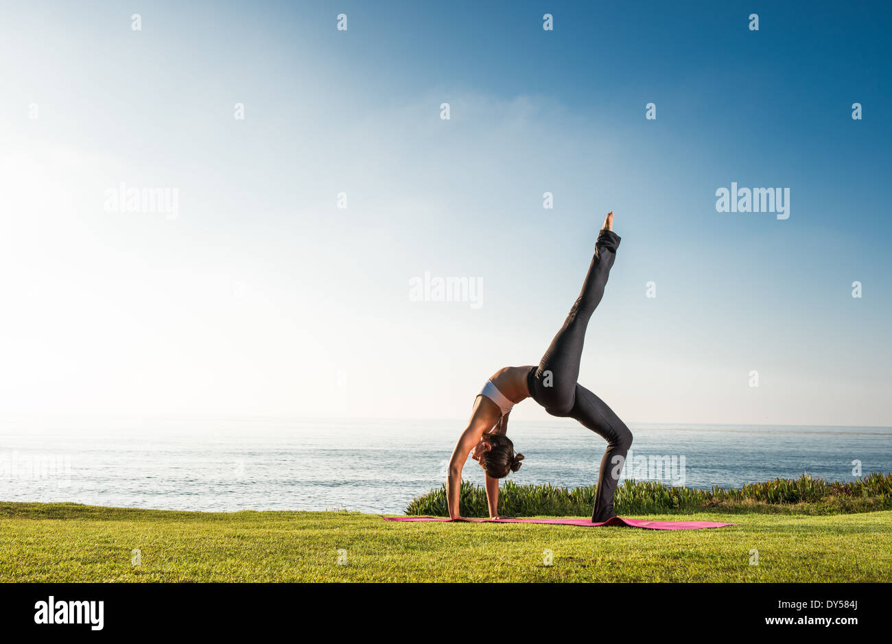 Women on cliff, in yoga position Stock Photo