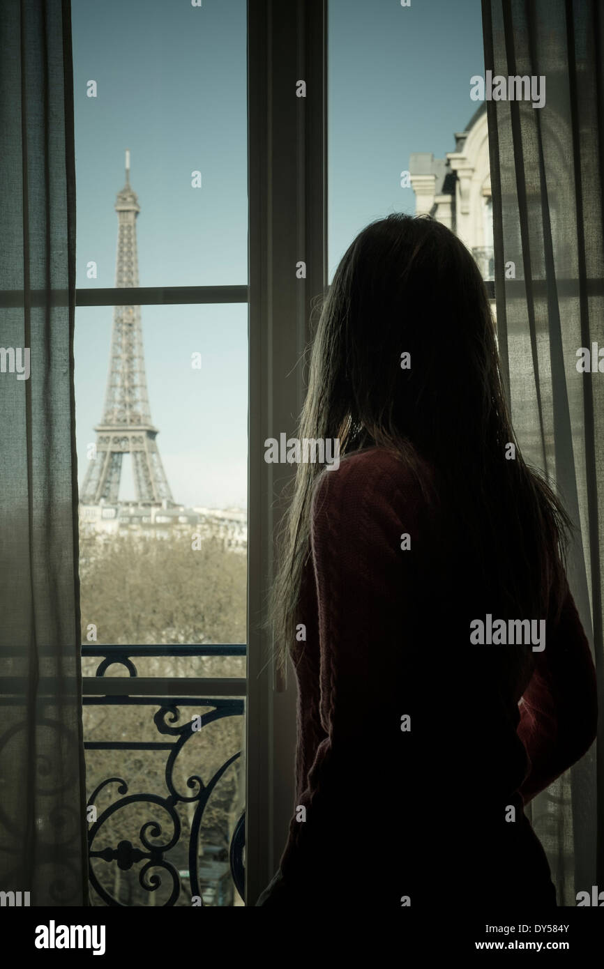 The Eiffel Tower, Paris, France, viewed by a woman through a window. Stock Photo