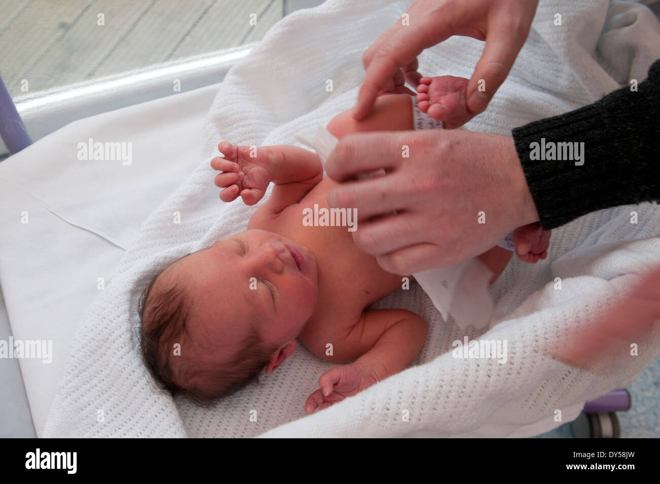 Newborn baby girl being dressed for the first time by her father Stock Photo