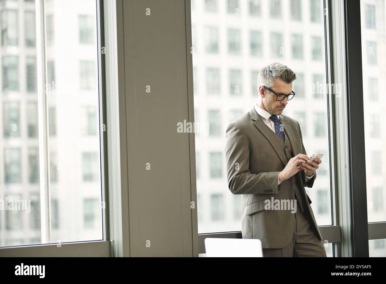 Businessman texting on smartphone in office Stock Photo