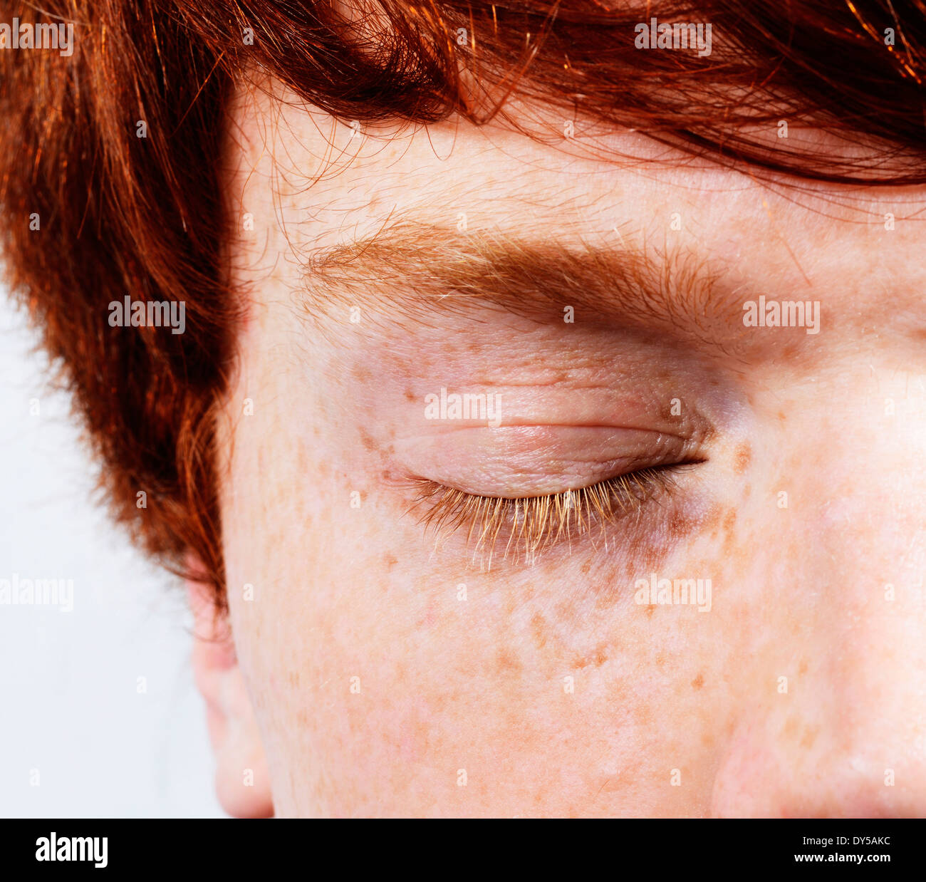 Partial facial shot of young man with red hair and freckles, eyes closed Stock Photo