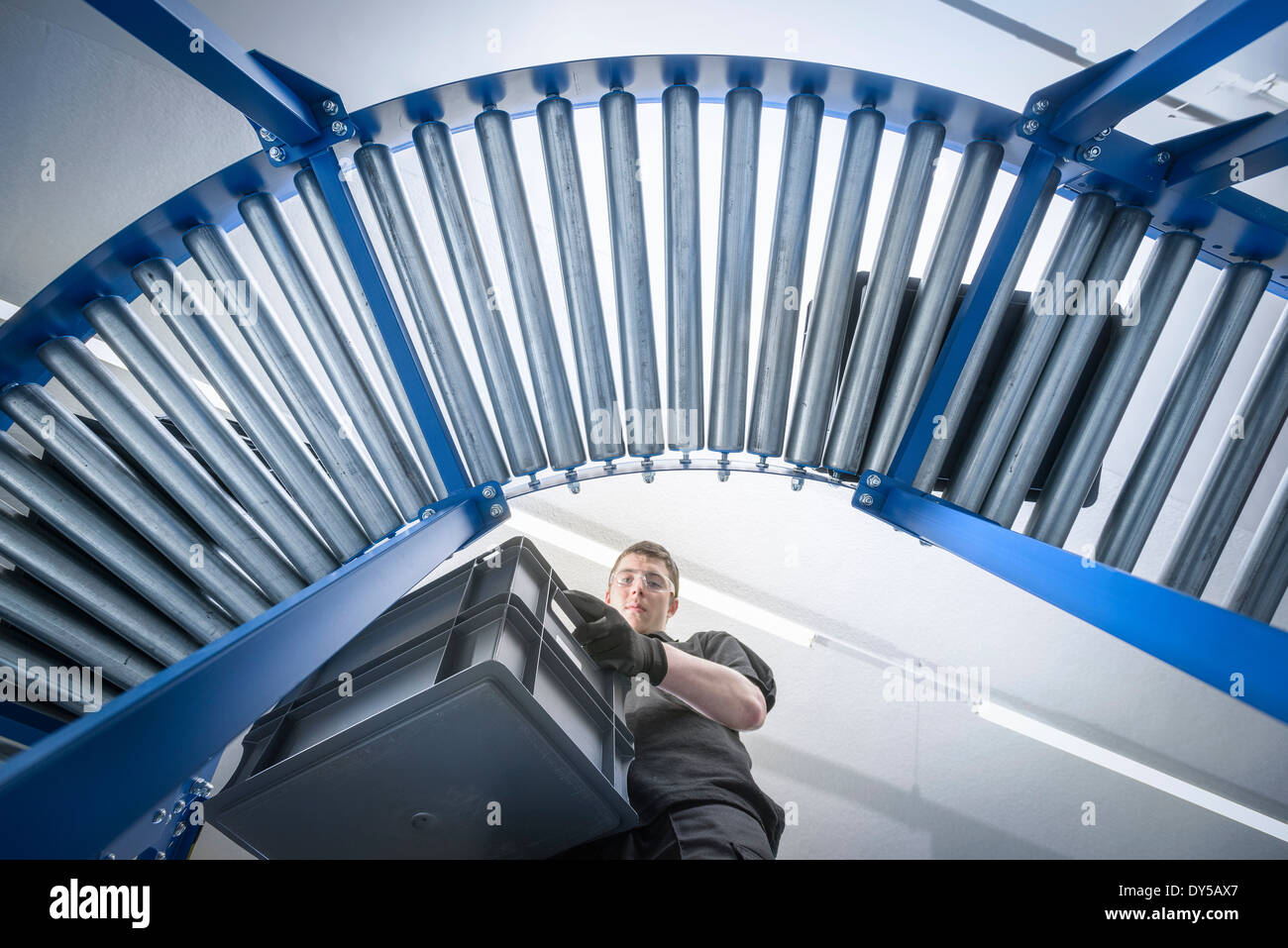 Low angle view of apprentice with crates on production line Stock Photo