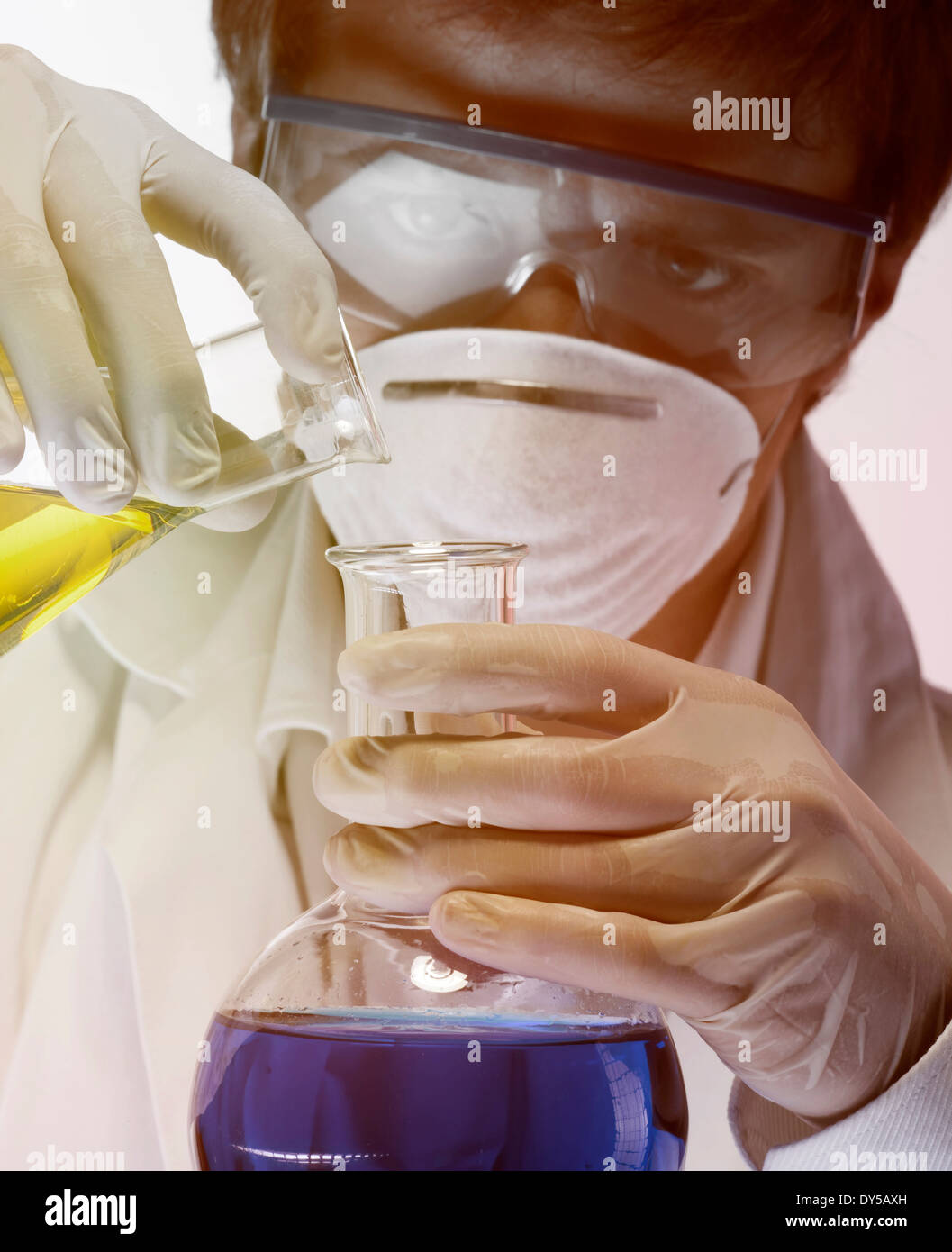 Young scientist carefully pouring liquid from flask Stock Photo