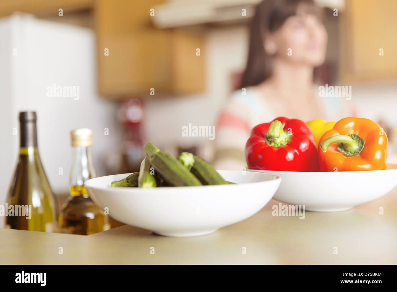 Mid adult woman in kitchen with bowls of vegetables on counter Stock Photo