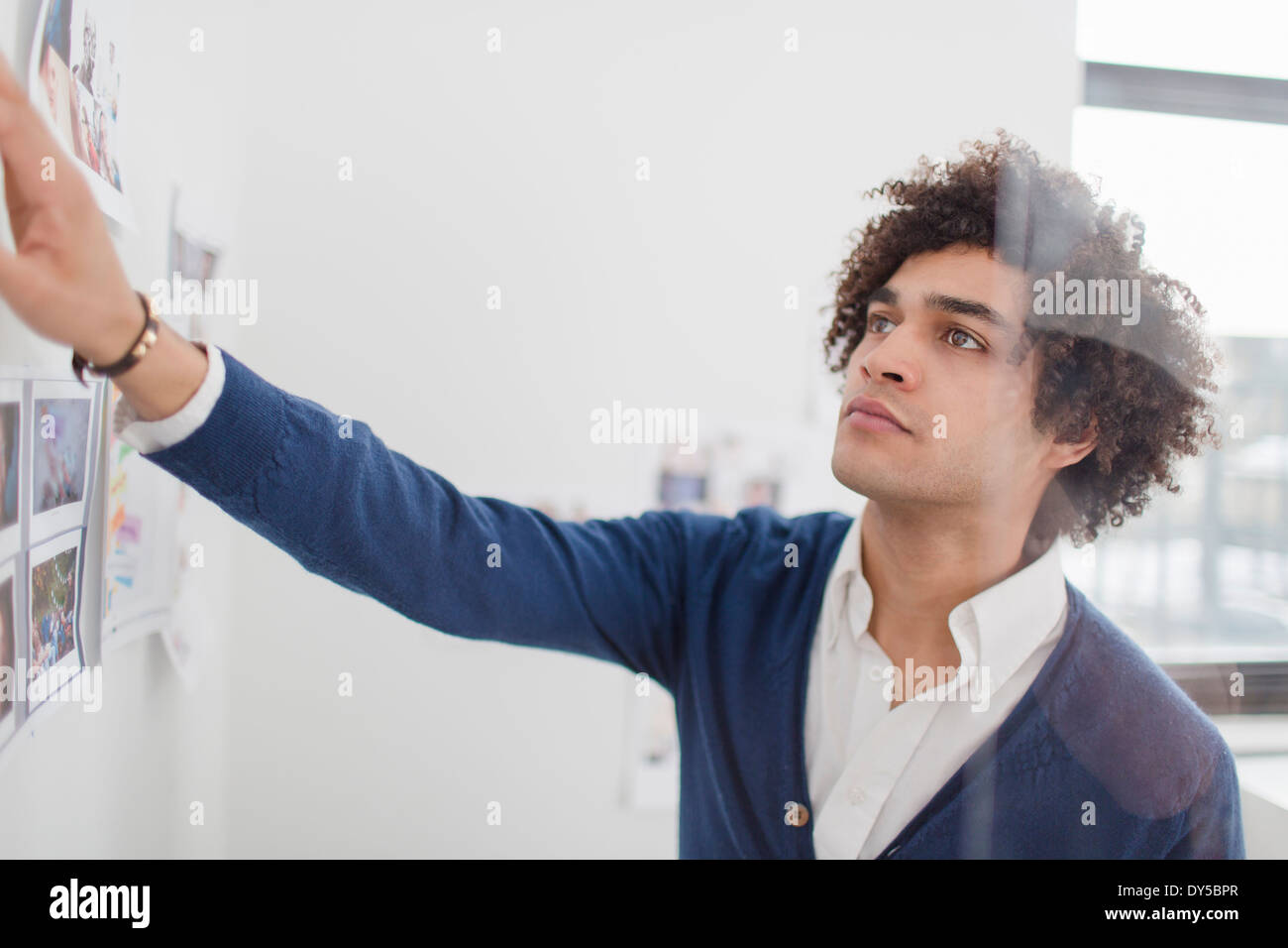 Young man looking at images on wall Stock Photo