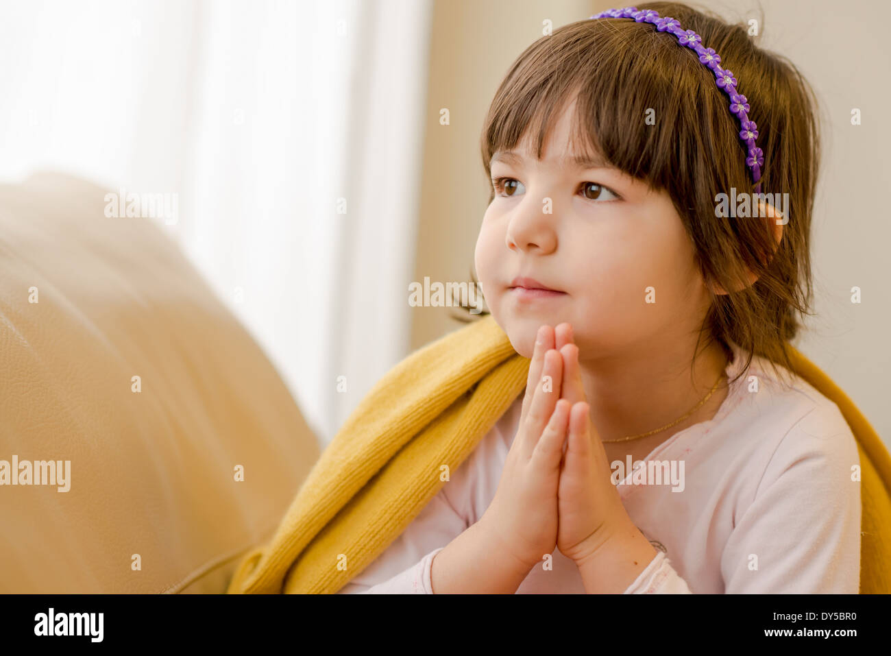 Young girl sitting on sofa daydreaming Stock Photo