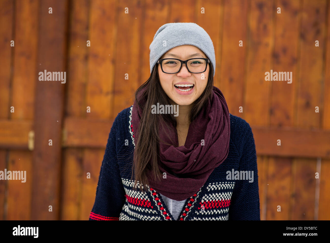 Portrait of young woman in front of wooden fence Stock Photo