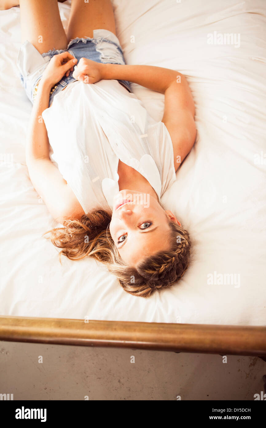 Young woman lying on bed looking at camera Stock Photo