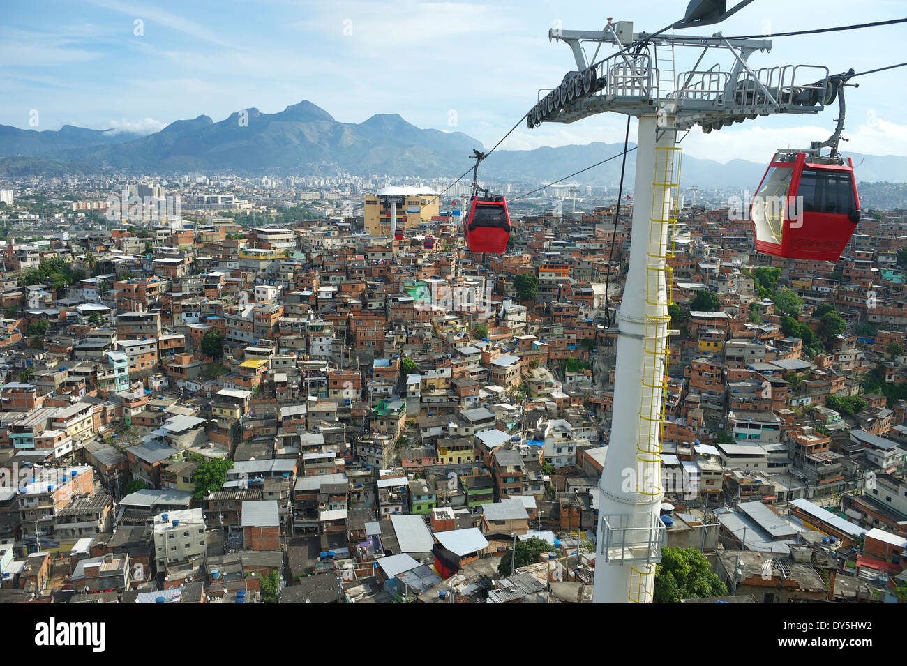 Red cable cars travel above Rio de Janeiro favela Complexo Alemao Stock Photo