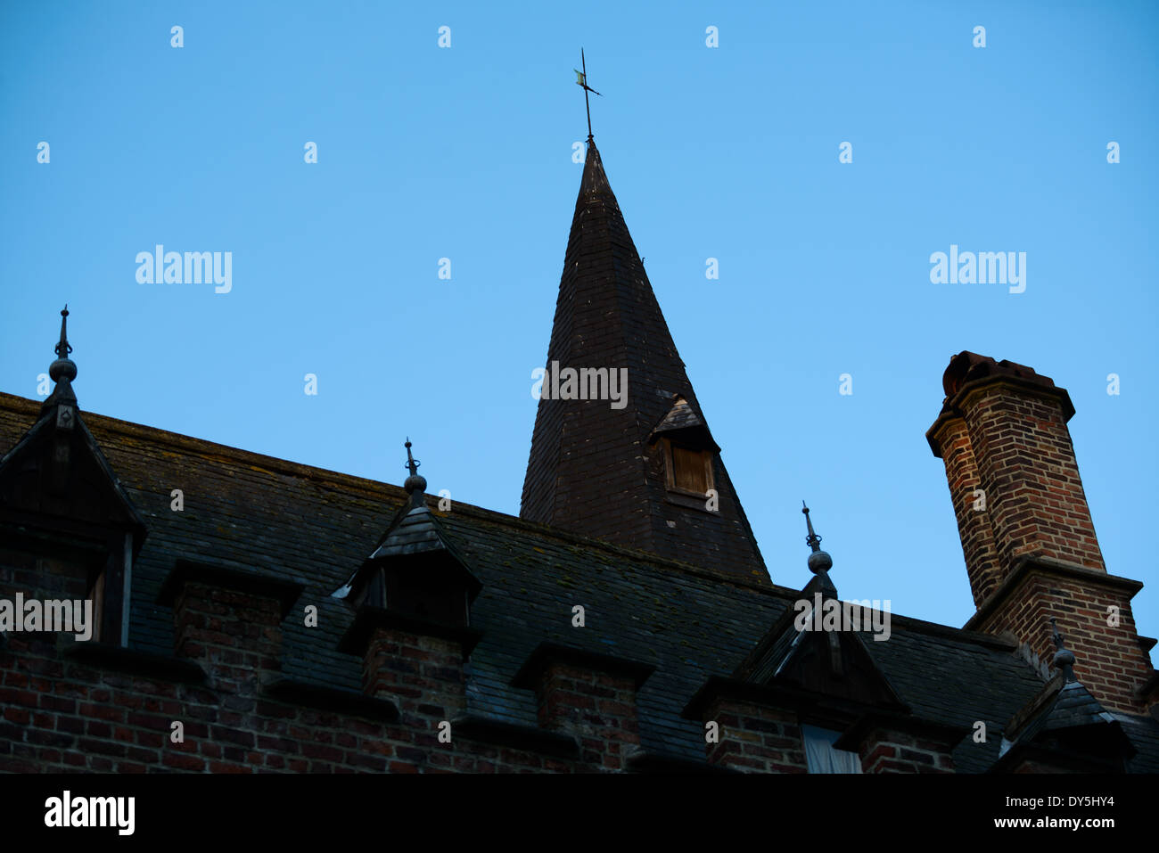 BRUGES, Belgium — A medieval turret and historic roofline in Bruges' Burg Square stands silhouetted against the pre-dawn sky. The architectural details of this historic structure demonstrate the elaborate design elements typical of medieval Flemish architecture. The early morning light emphasizes the distinctive profile of this significant building in one of Bruges' most important historic squares. Stock Photo