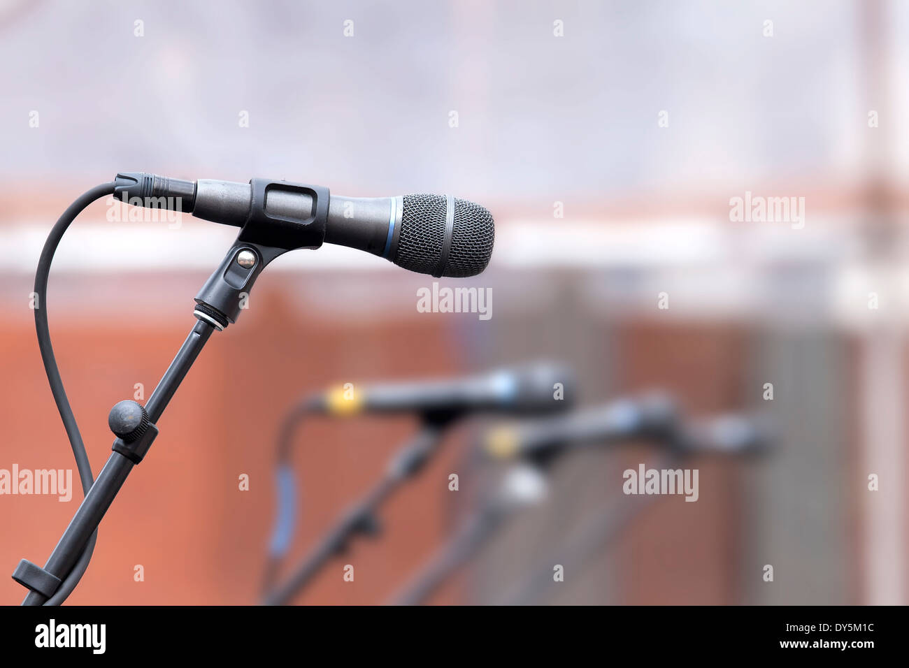 microphone row backup singers stage live performance stand blurred background equipment amplifier speech concert closeup Stock Photo