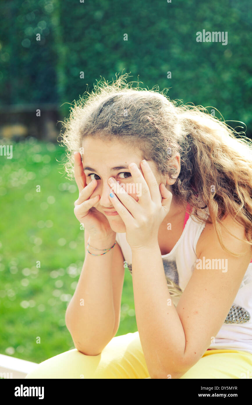 Blond curly teenager looking through her fingers Stock Photo