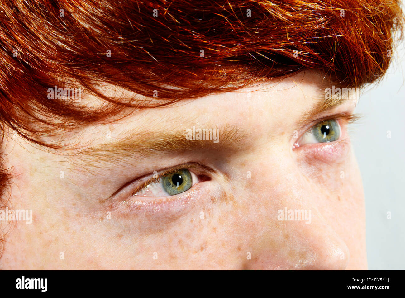 Upper facial shot of young man with red hair, freckles and green eyes looking up Stock Photo