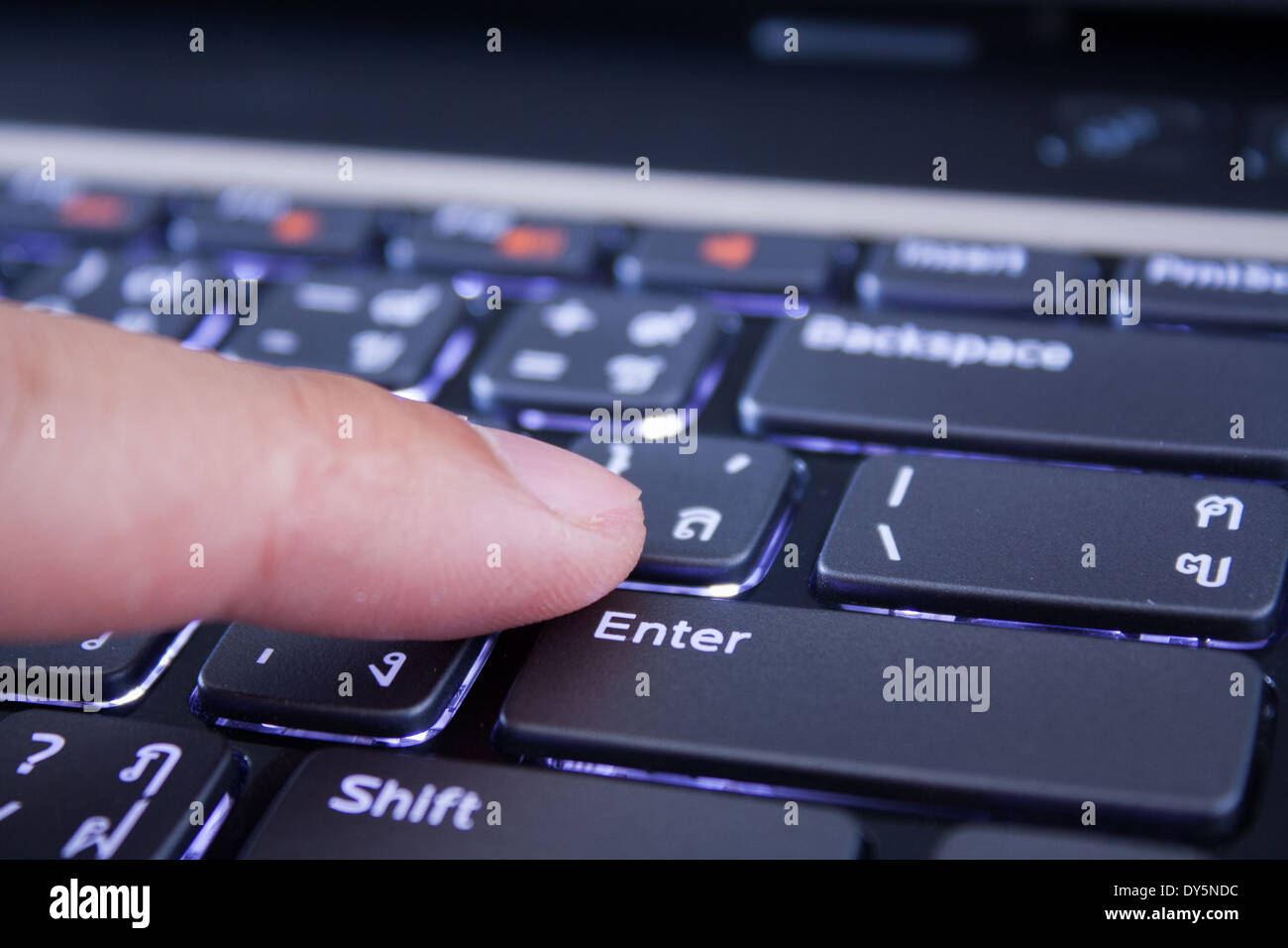 a finger is pushing the enter button Stock Photo