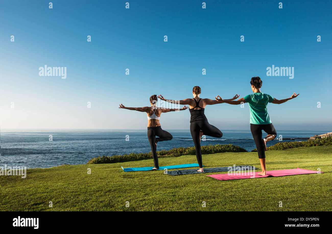 Women on cliff, in yoga position Stock Photo