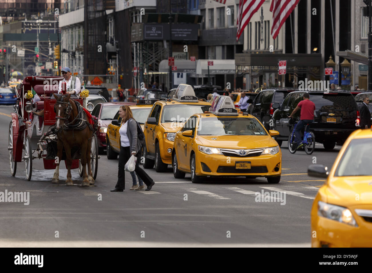 Pedestrians on crosswalk yellow taxis and horse and carriage waiting Stock Photo