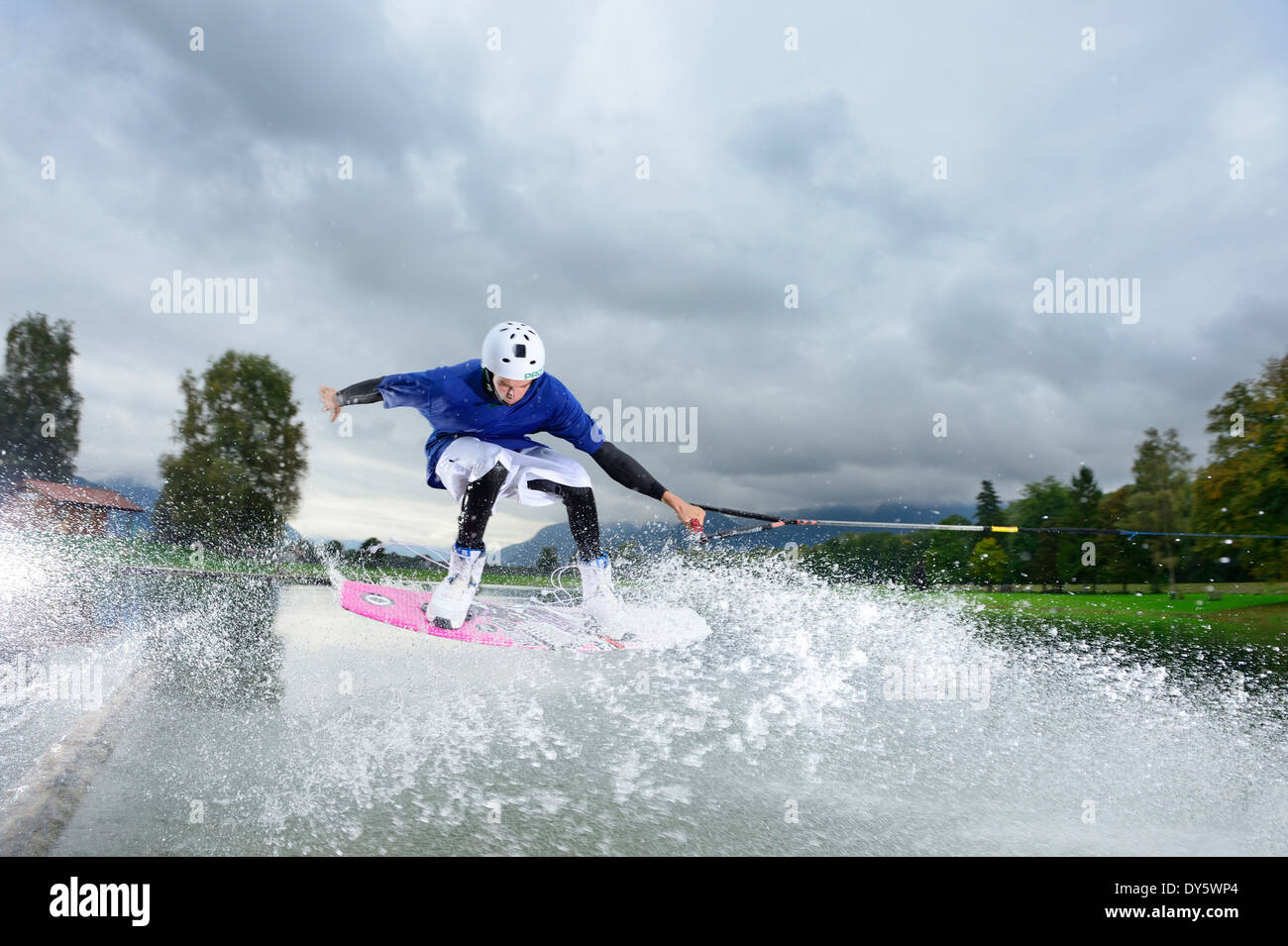 Young man surfing on wakeboard, wakeboarding at lake Neubeurer See, Neubeuern, Rosenheim, Upper Bavaria, Bavaria, Germany Stock Photo