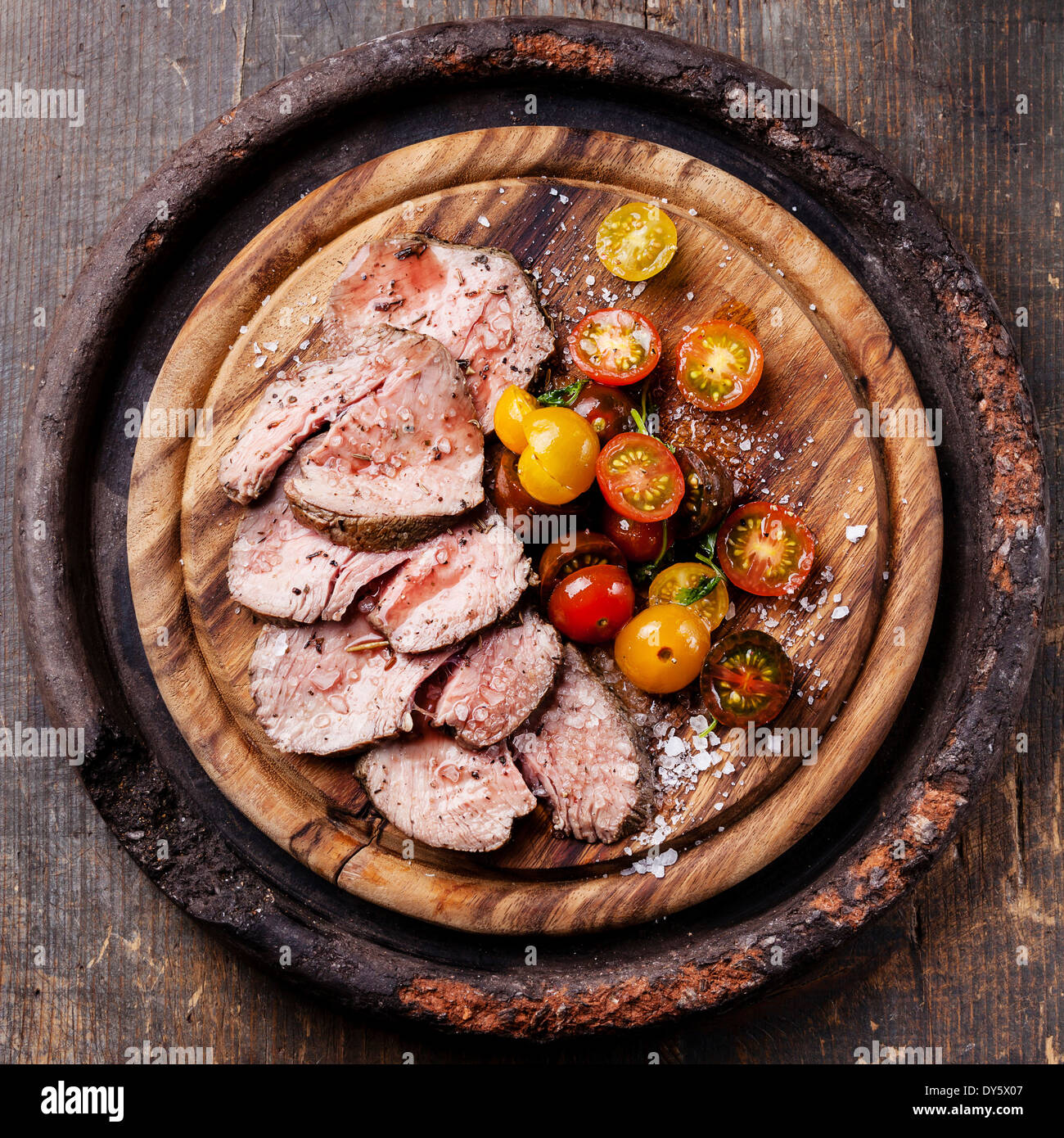 Roast beef with cherry tomatoes on cutting board Stock Photo