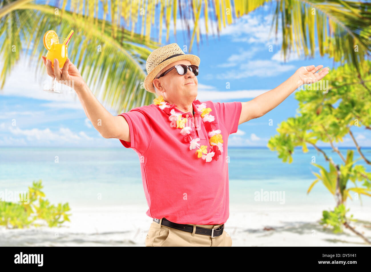 mature-man-holding-a-cocktail-and-gesturing-joy-on-a-sunny-beach-DY5Y41.jpg