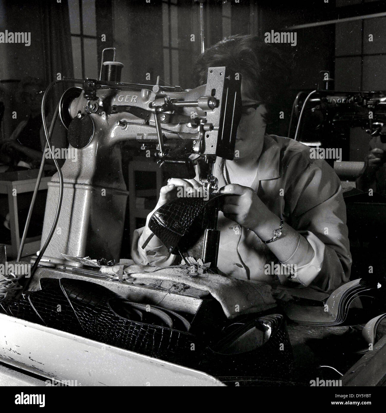 1950s, historical, a female worker using an industrial Singer sewing machine to sew or stitch a leather shoe at the Glenfield Progress Co-Operative Society limited, a boot and shoe business in Glenfield, Leicester, England, UK. The business specialised in women's and children's footwear. Historically Leicestershire was an important area of Britain for shoe manufacture and in 1872 the Co-operative Wholesale Society began making shoes there. Invented by Isaac Singer in the 1820s, originally for stitching cloth, he produced a version in the 1840s that was strong enough for leather. Stock Photo