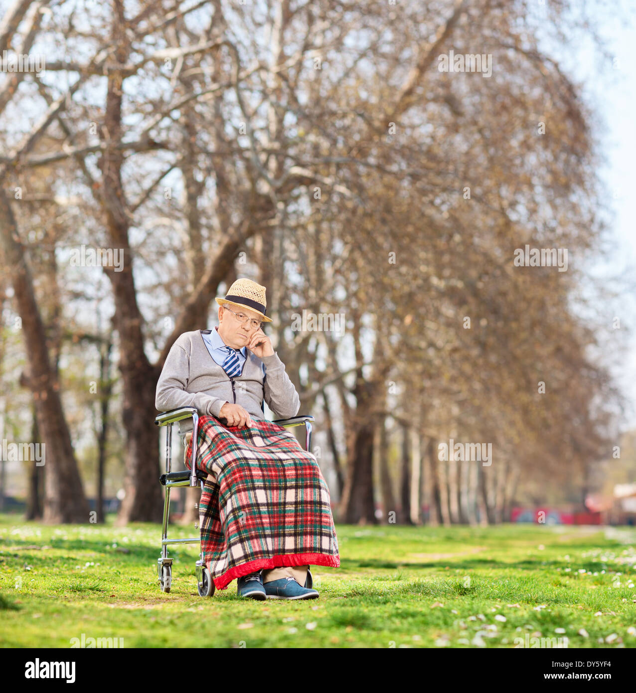 Worried senior sitting in a wheelchair in park Stock Photo