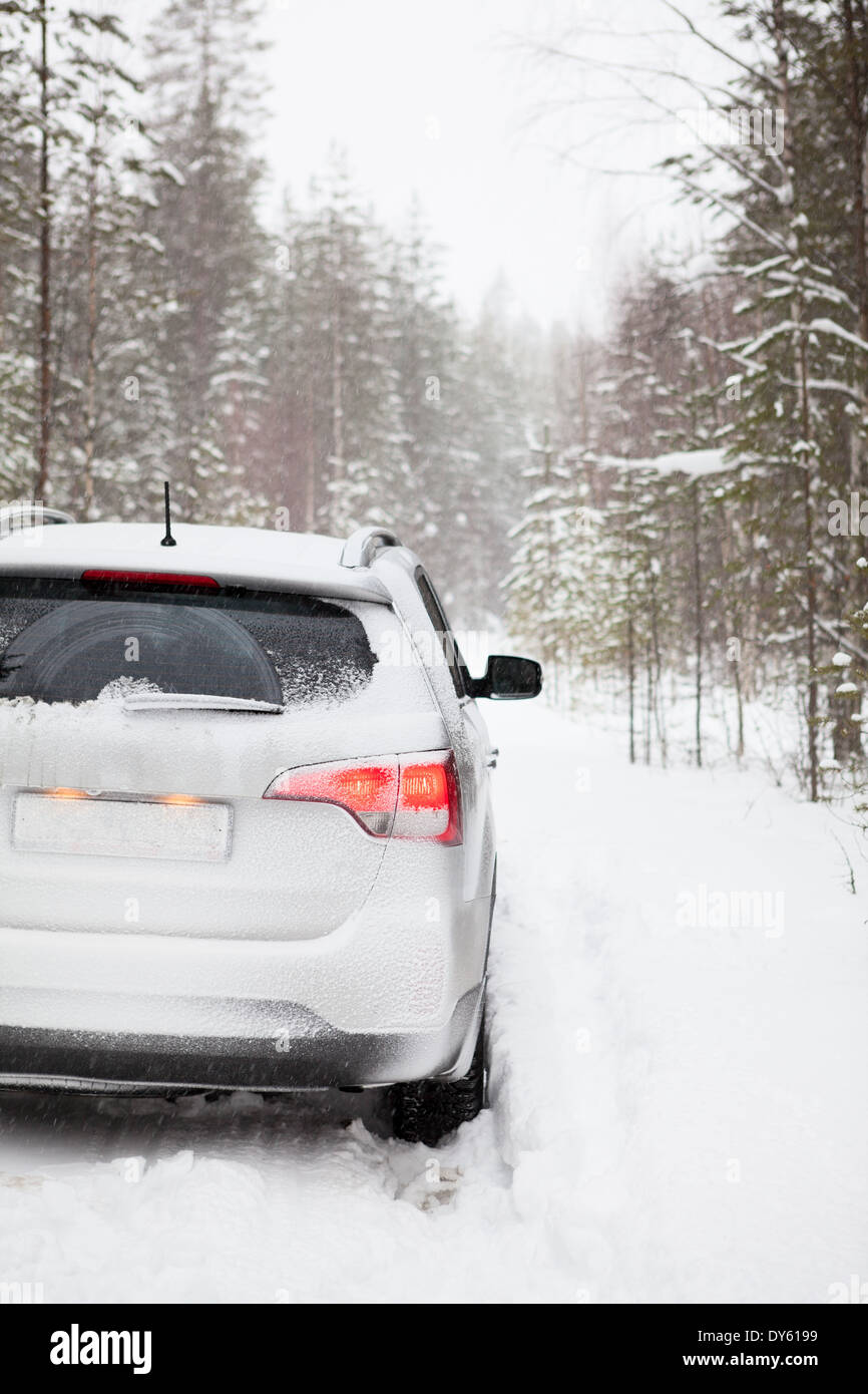 Icy offroad car standing on snowy forest road, rear view Stock Photo