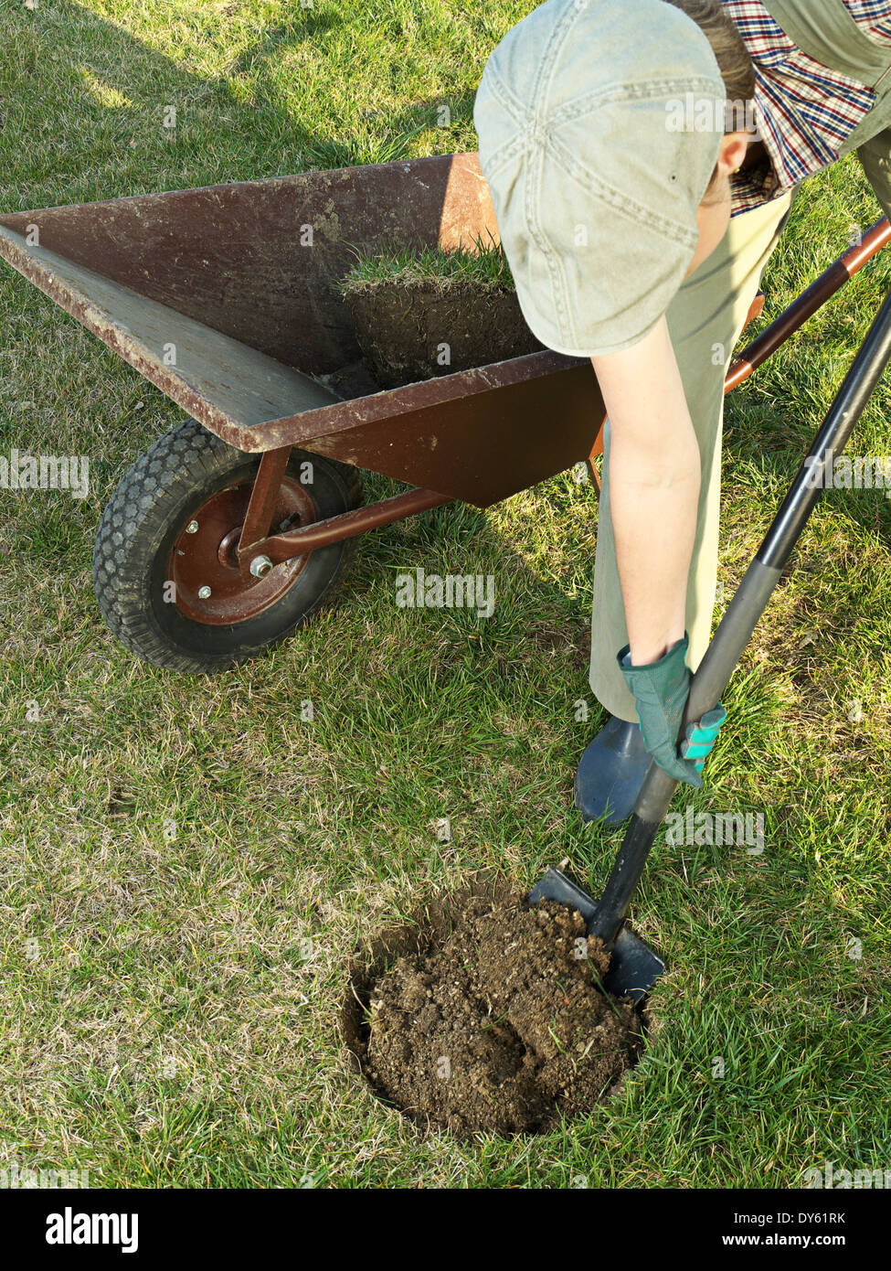 Female gardener digging a hole with spade in the garden Stock Photo