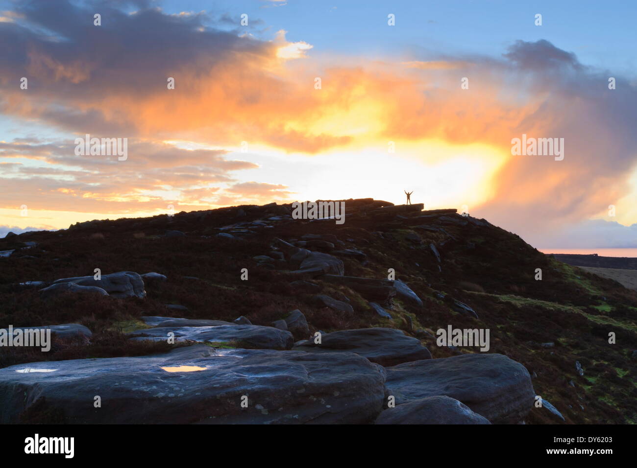 Person on rocks of Stanage Edge with winter sunrise, near Hathersage, Peak District National Park, Derbyshire, England, UK Stock Photo