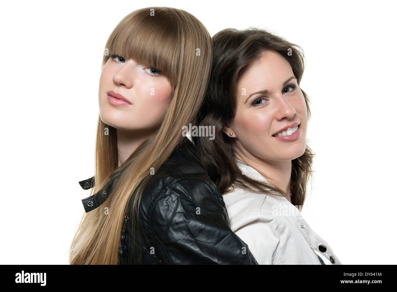 Two happy women blonde and brunette, with black and white leather jacket, standing back to back Stock Photo