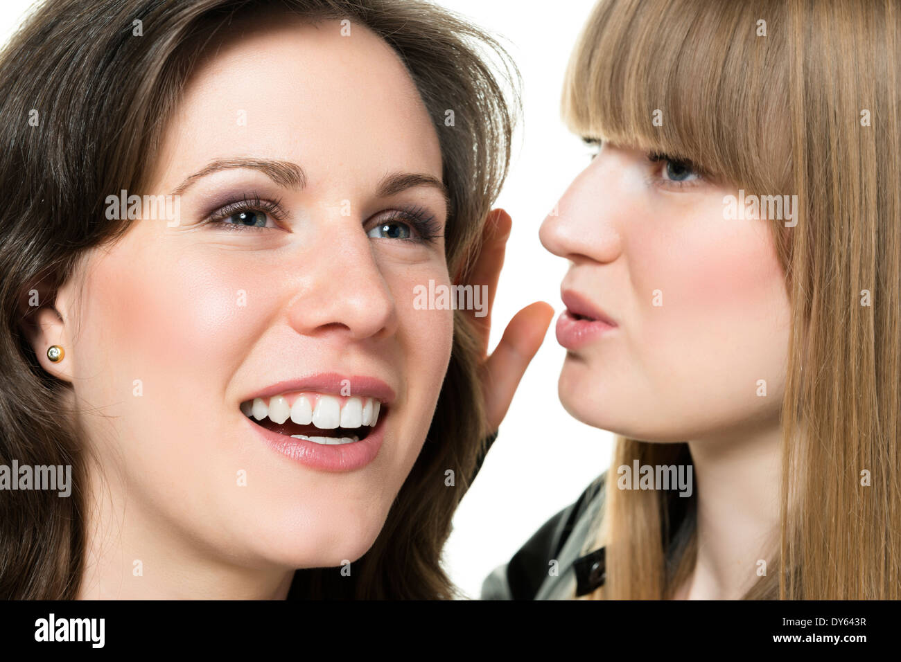 Two women blonde and brunette, with black and white leather jacket, one whispers to the other something Stock Photo