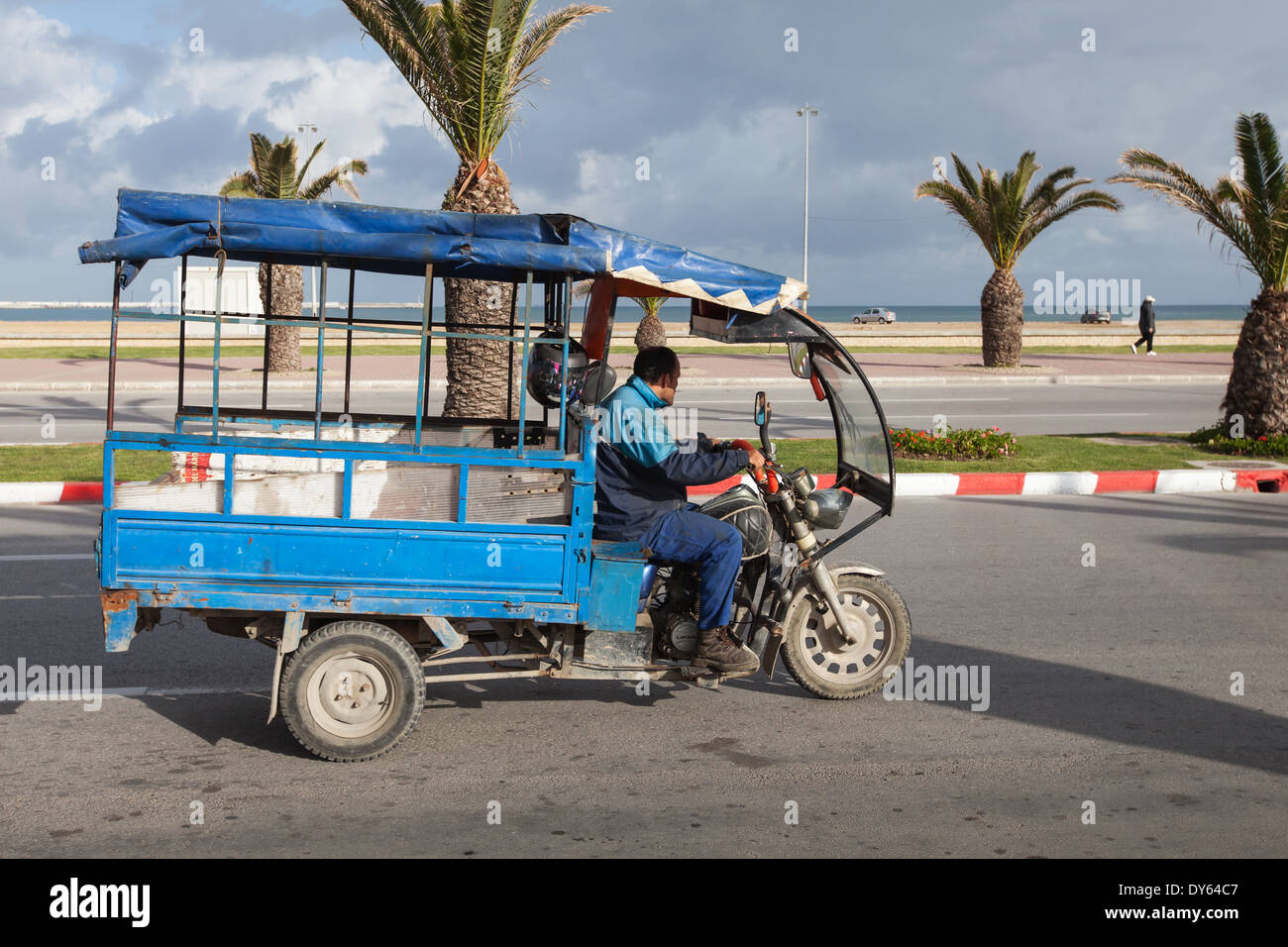 TANGIER, MOROCCO - MARCH 27, 2014: old blue tricycle cargo bike with Arab driver rides on the coastal street of  Tangier Stock Photo