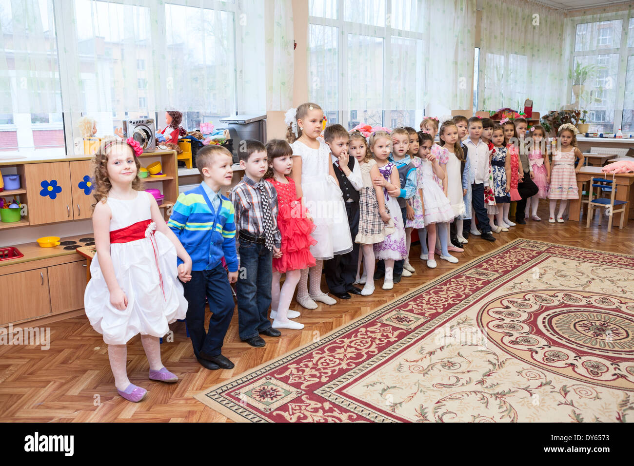 Boys and girls dance waltz in pairs on theater stage in kindergarten, Russia. Graduation party is in daycare center Stock Photo