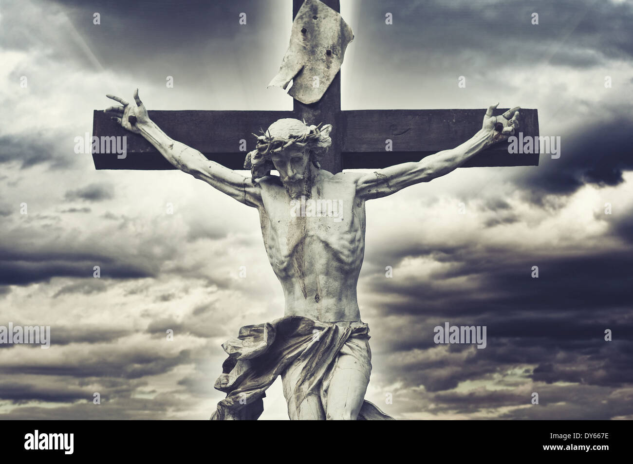 Crucifixion. Christian cross with Jesus Christ statue over stormy clouds. religion and spirituality concept. Stock Photo