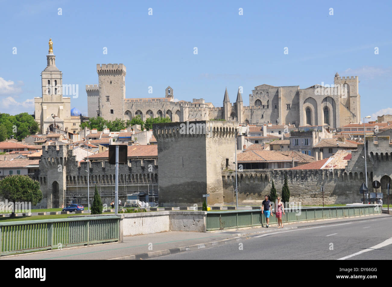 Two people crossing the Pont Edouard Daladier, with the Palais des Papes in the background, Avignon, Stock Photo