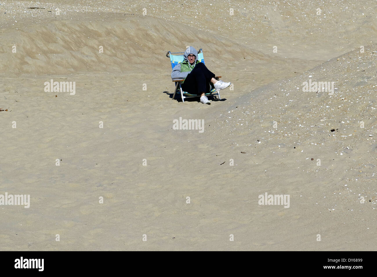 Man sits alone on the beach on a chilly day Stock Photo