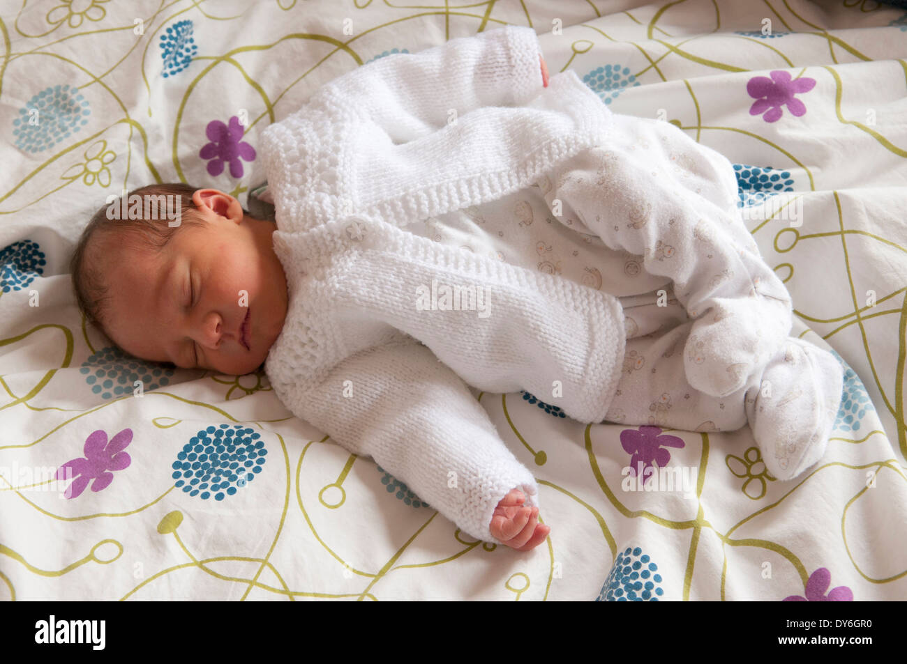 Two day old newborn baby girl lying asleep on bed Stock Photo