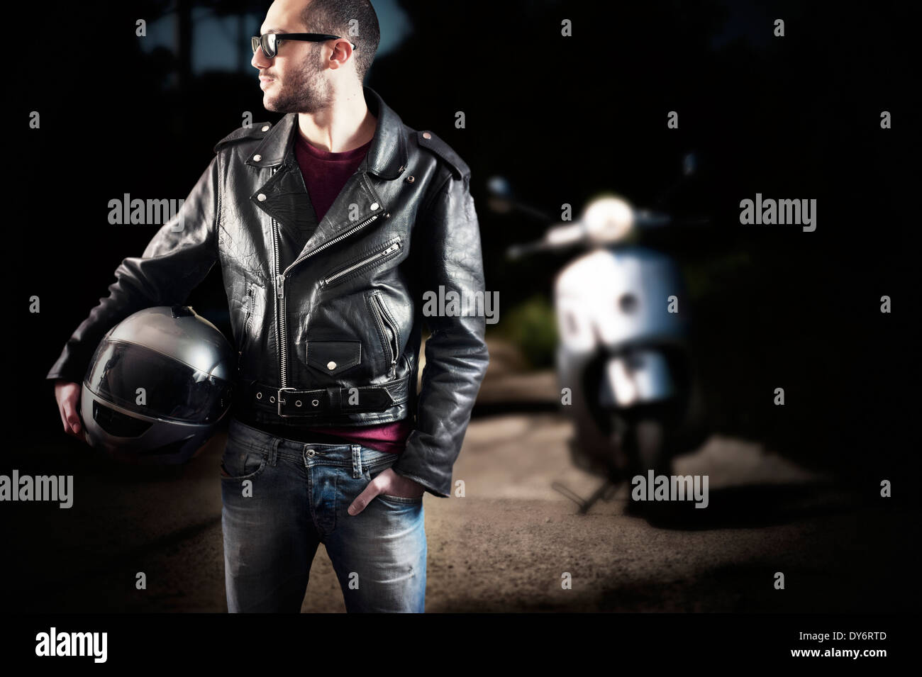 Biker in leather jacket posing with his scooter Stock Photo