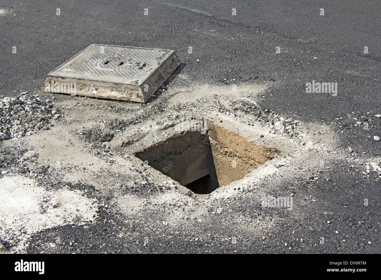 Open unsecured sewer manhole in the street Stock Photo