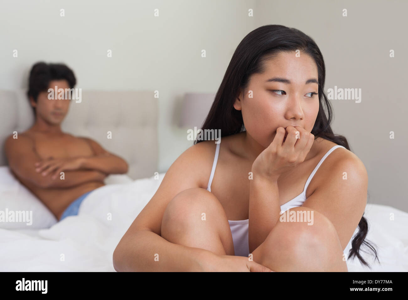 Boyfriend looking at upset girlfriend sitting on end of bed Stock Photo