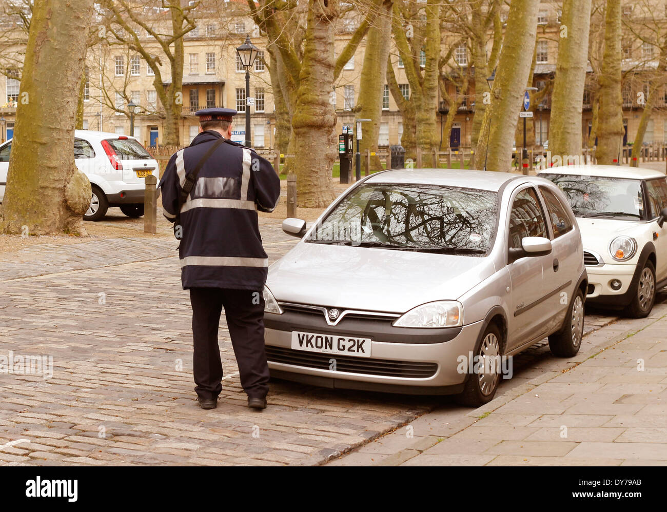 Traffic Warden issuing a traffic parking ticket early on a Saturday morning, in Queens Square, Bristol, England, 5 April 2014 Stock Photo