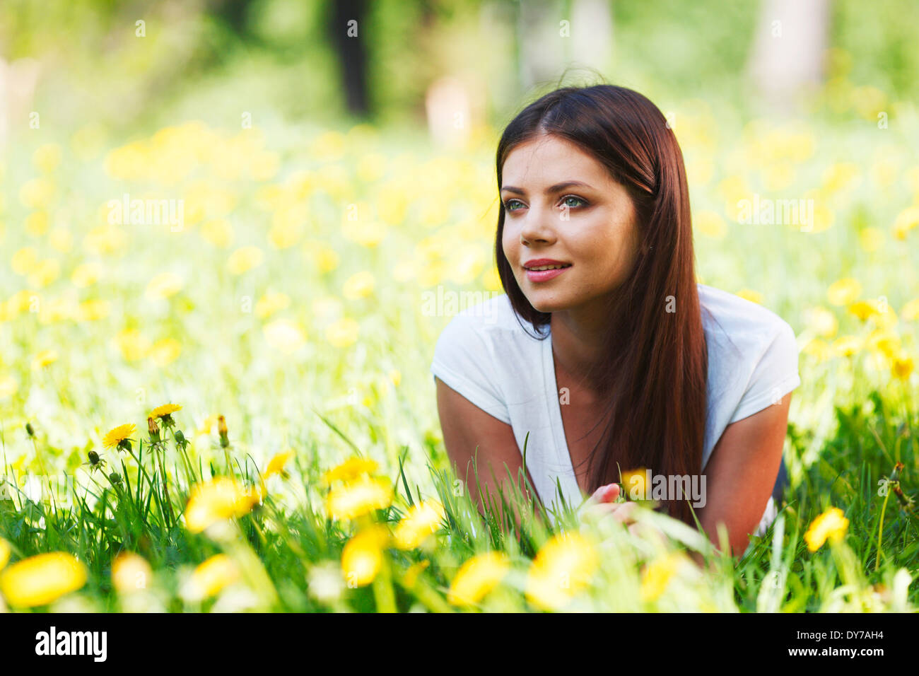 Beautiful young woman lying on grass with flowers Stock Photo - Alamy