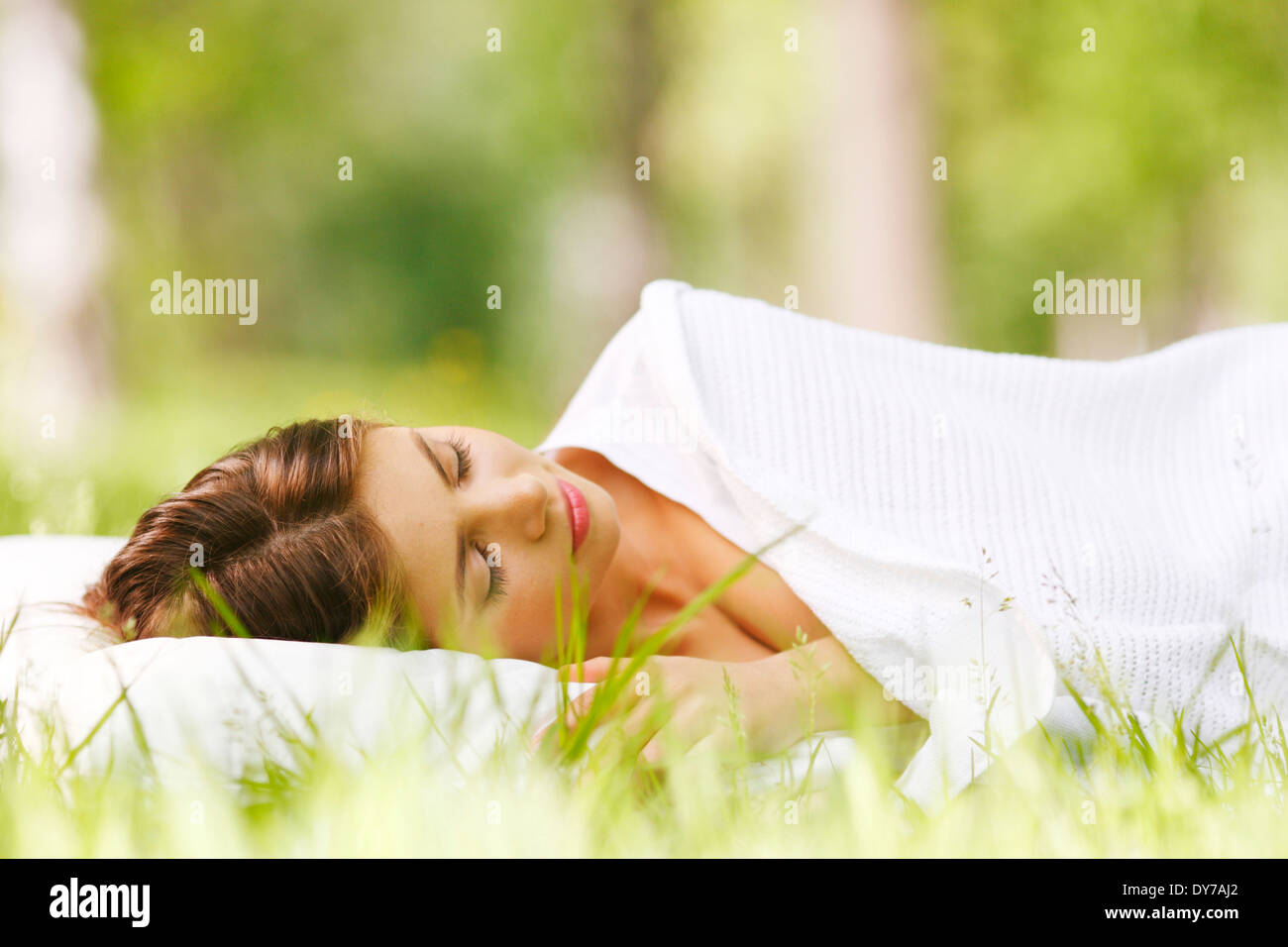 Young woman sleeping on soft pillow in fresh spring grass Stock Photo