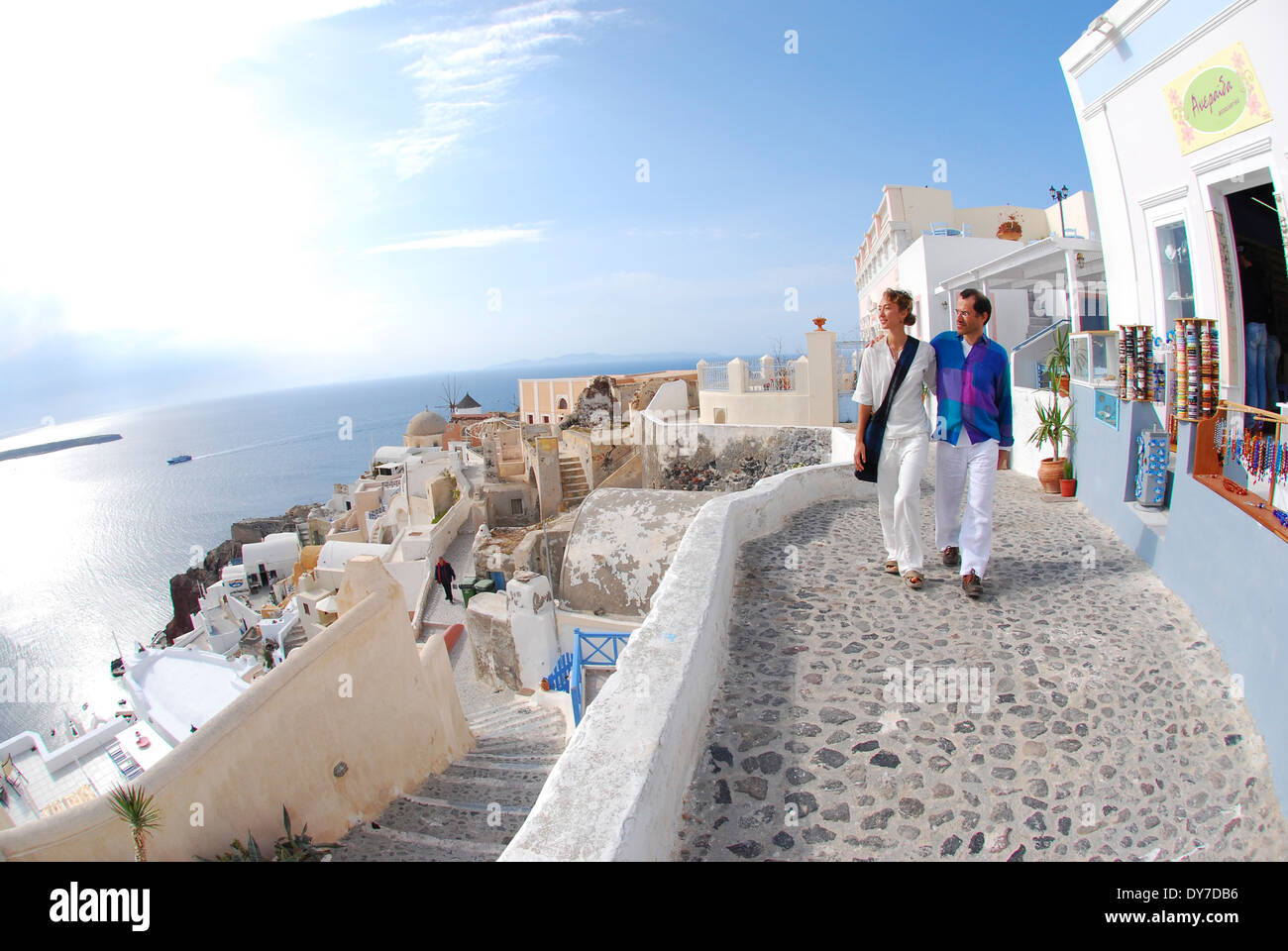 A couple strolling past a storefont and enjoying the view in Oia, Santorini, Greece. Stock Photo