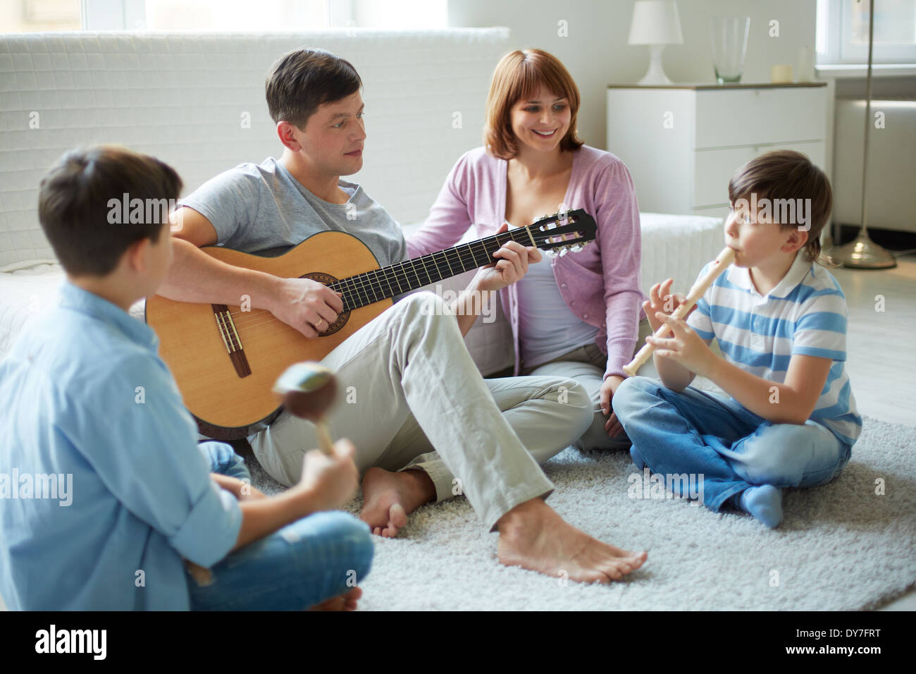 Portrait of handsome siblings and their father playing musical instruments at home Stock Photo